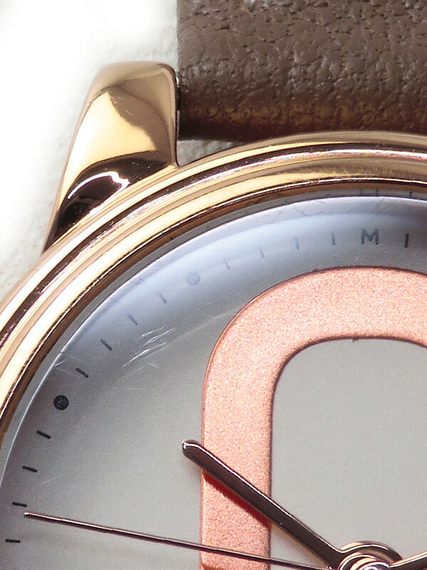 Close-up of Corie watch dial showing rose gold logo and hour markers with brown leather strap