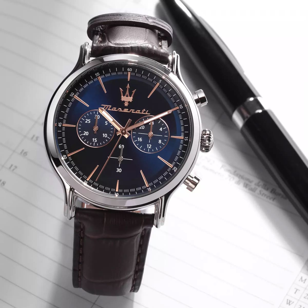 Maserati Epoca chronograph watch on white paper surface showcasing blue dial and stainless steel case