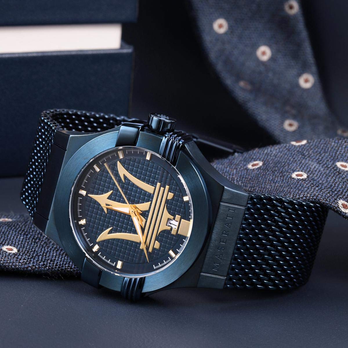 Close-up of blue dial with gold trident logo, hour markers, and gold hands