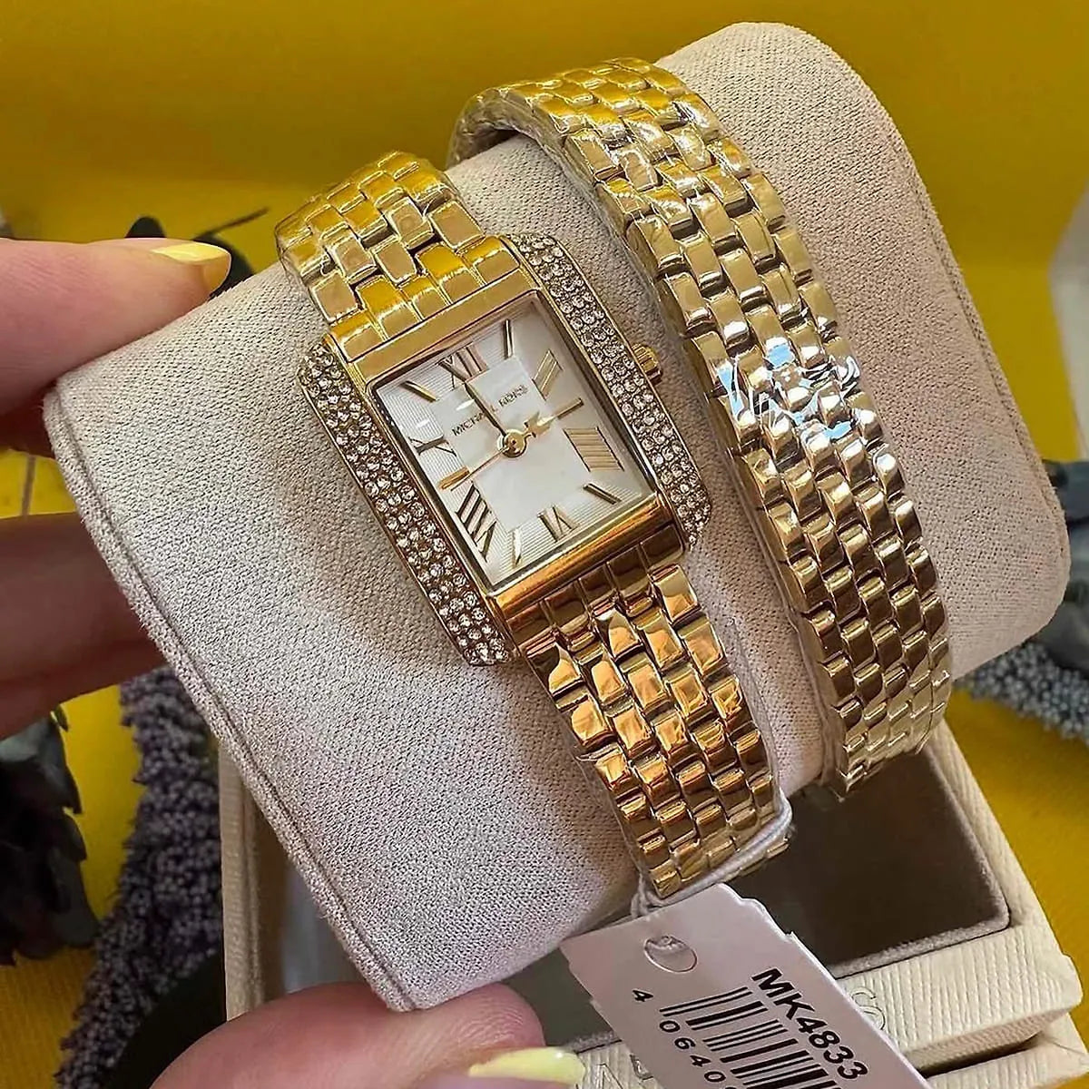 Michael Kors Emery MK4833 double wrap gold bracelet watch on wrist with display holder