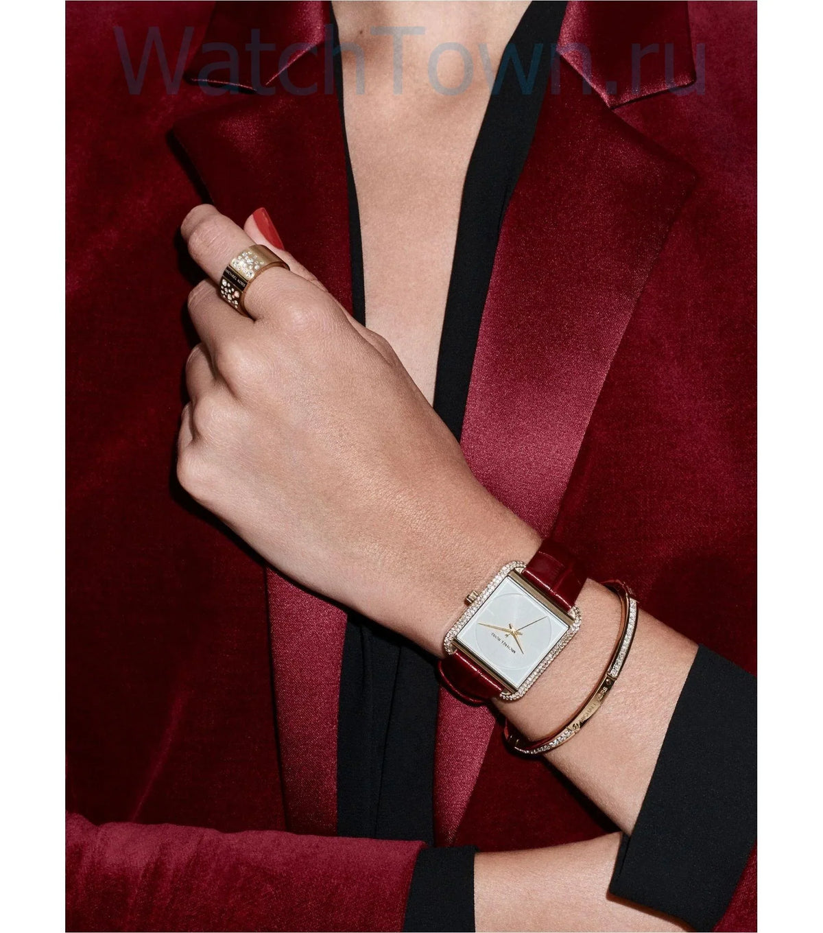 Michael Kors Lake Glitz watch with red leather strap worn on wrist with burgundy velvet jacket