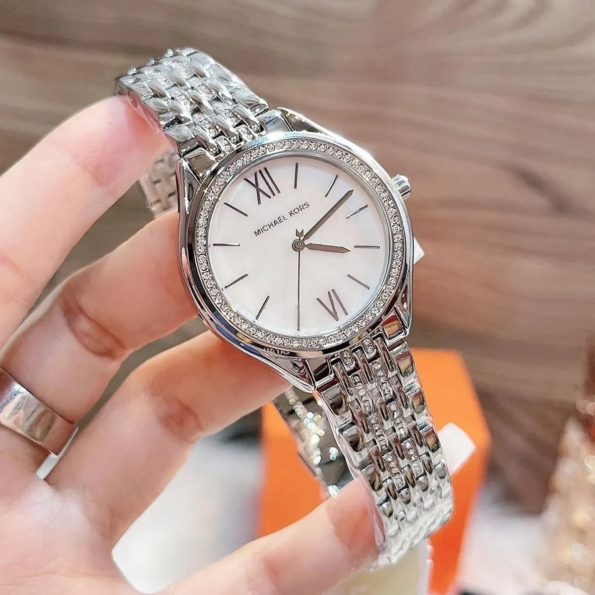 Michael Kors Mindy watch angled view displaying white dial, Roman numerals, and crystal bezel