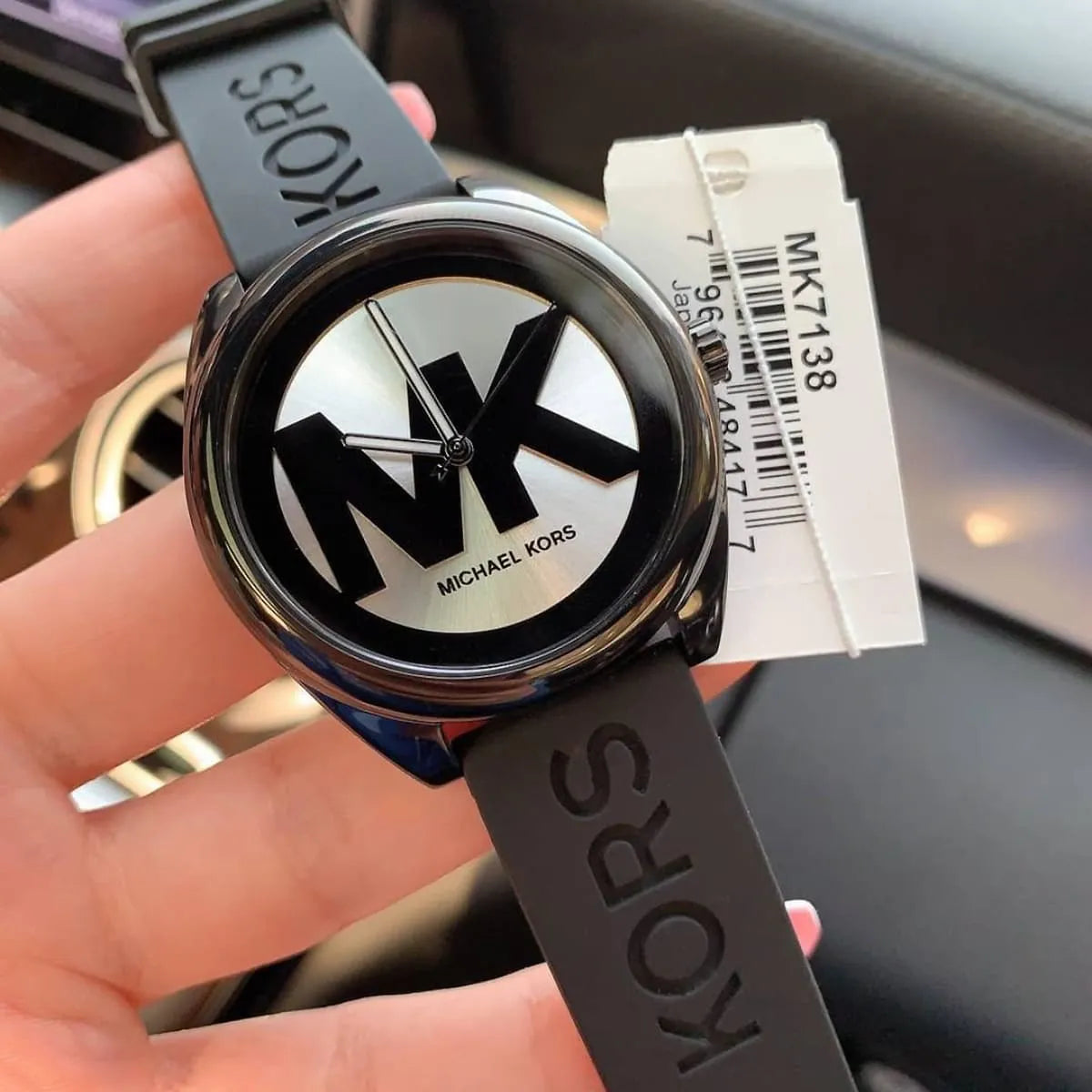 Michael Kors MK7138 watch on wrist with product tag attached to black rubber strap