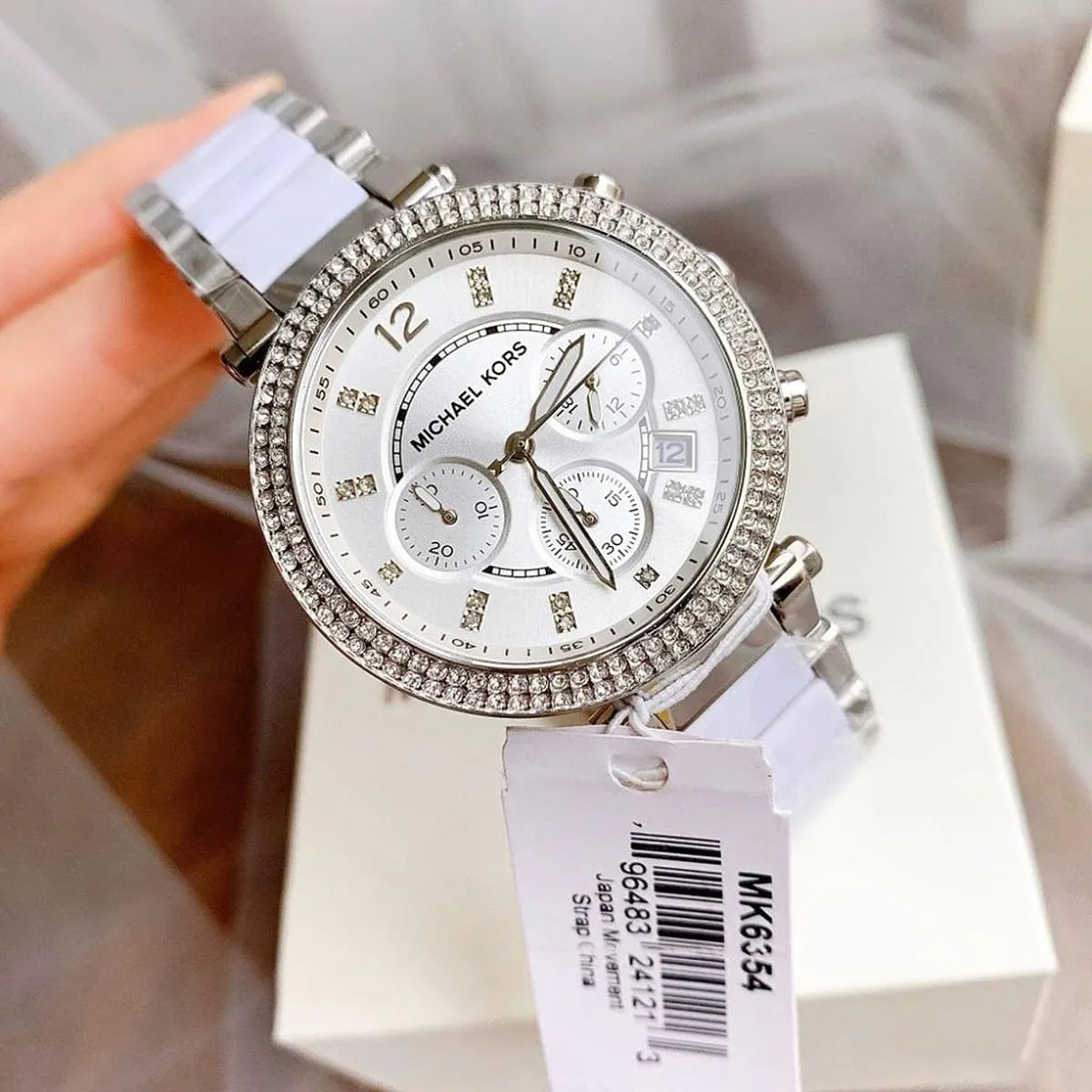 Michael Kors Parker MK6354 watch in hand with crystal bezel and white strap detail