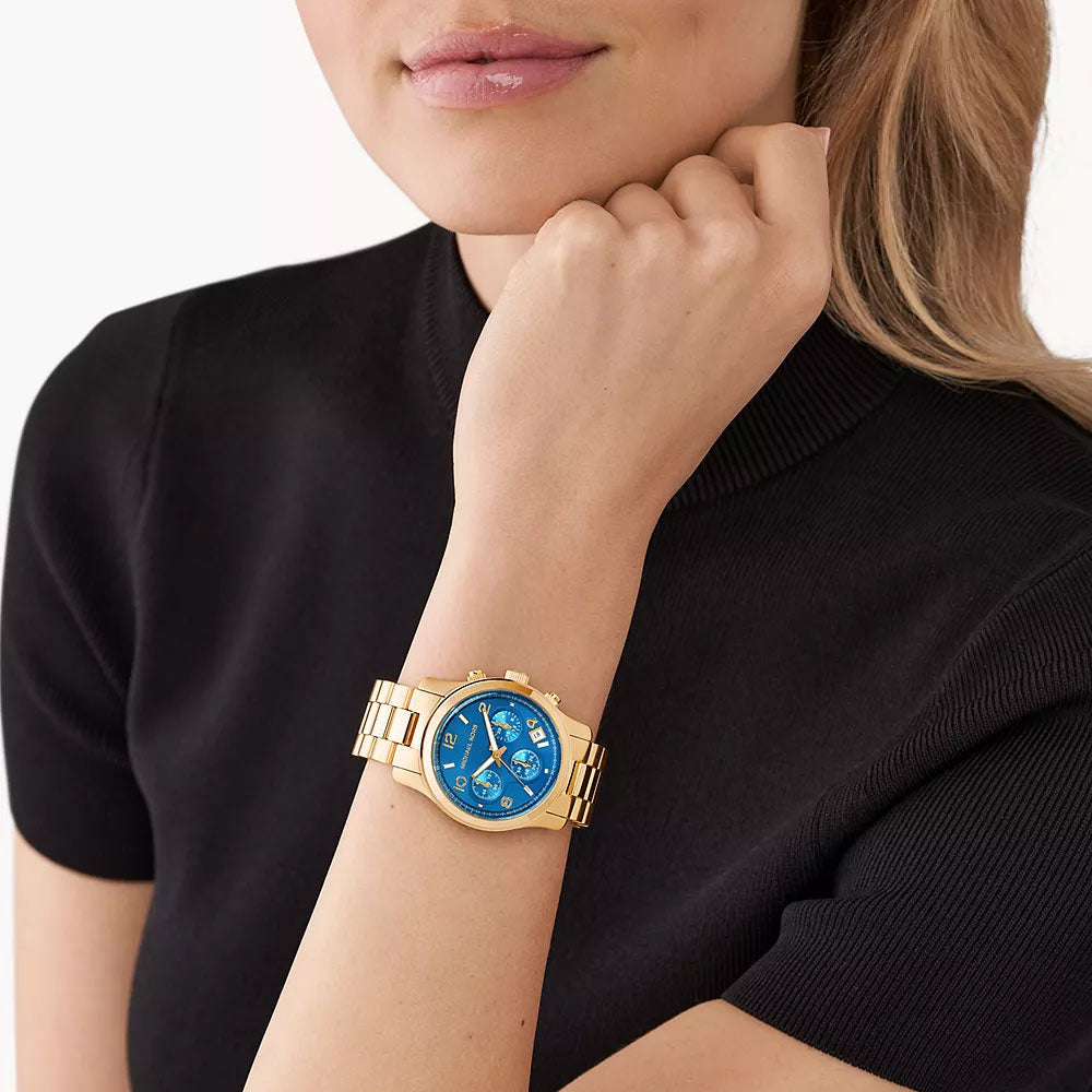Michael Kors Runway chronograph watch with gold-tone case and blue dial worn on wrist