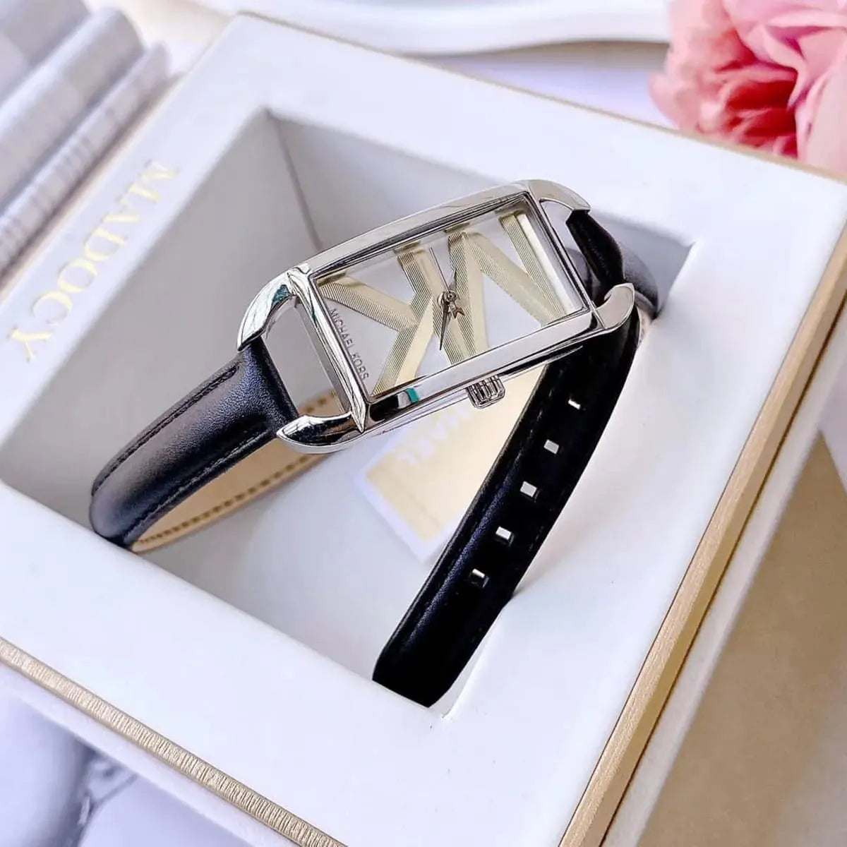 Mini Empire watch held in hand showing rectangular silver case and black double-wrap leather strap