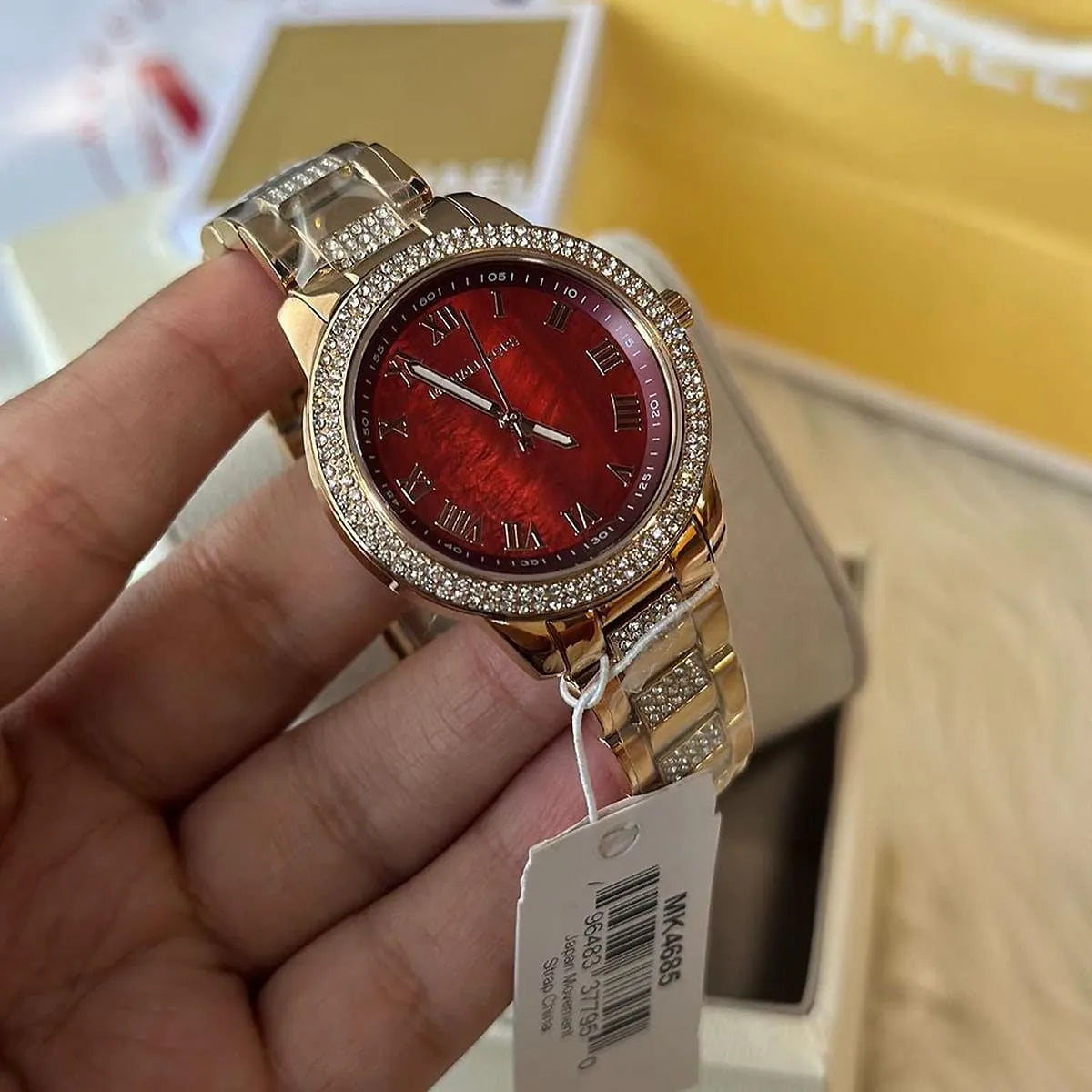 Michael Kors Tibby women's watch on wrist showing maroon dial with Roman numerals