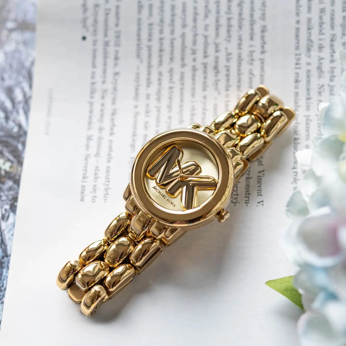 Michael Kors Phoebe gold-tone watch on wrist displaying three-hand dial and logo with link bracelet