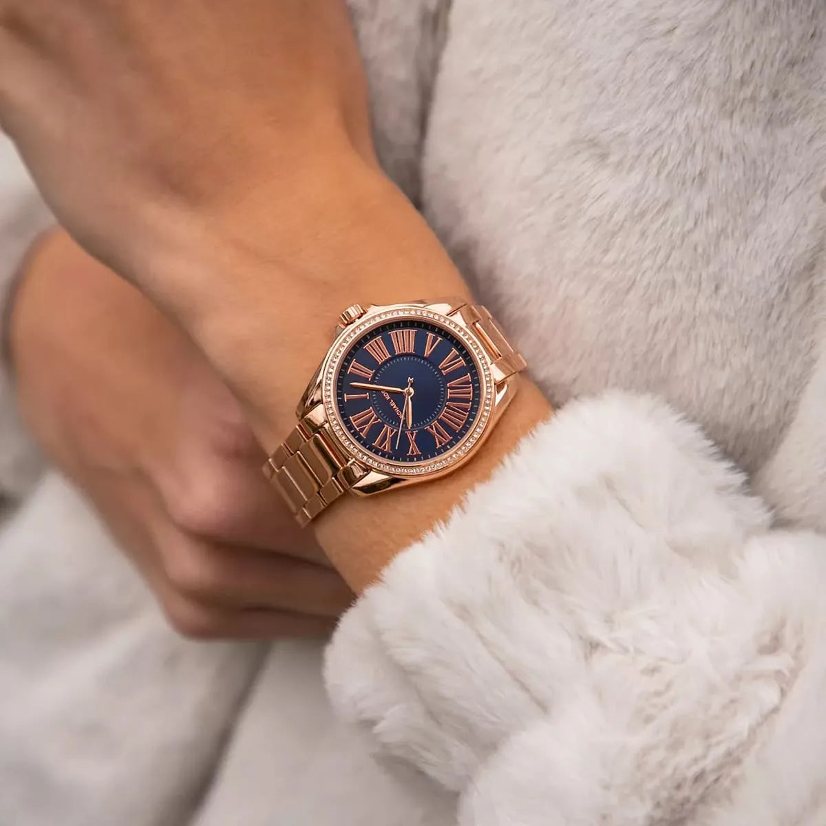 Michael Kors Kacie rose gold-tone watch on wrist with blue dial and Roman numeral indices