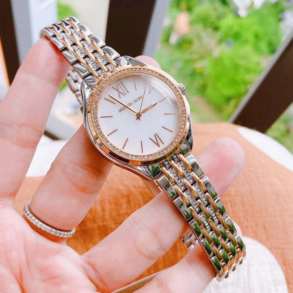 Mindy watch held in hand, showing detailed view of crystal-set bezel, two-tone strap, and Roman numeral dial