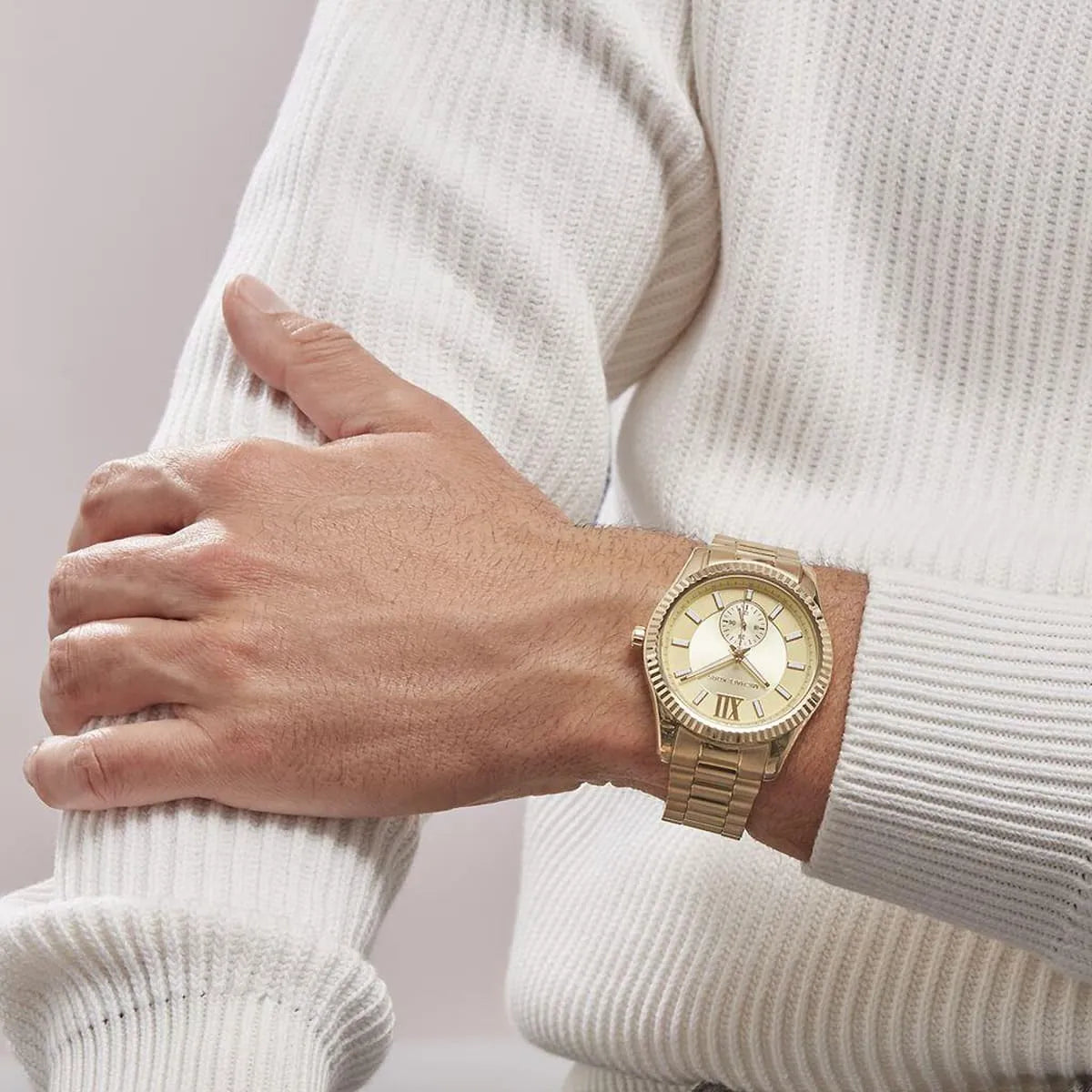Michael Kors Lexington gold watch on wrist with cream sweater