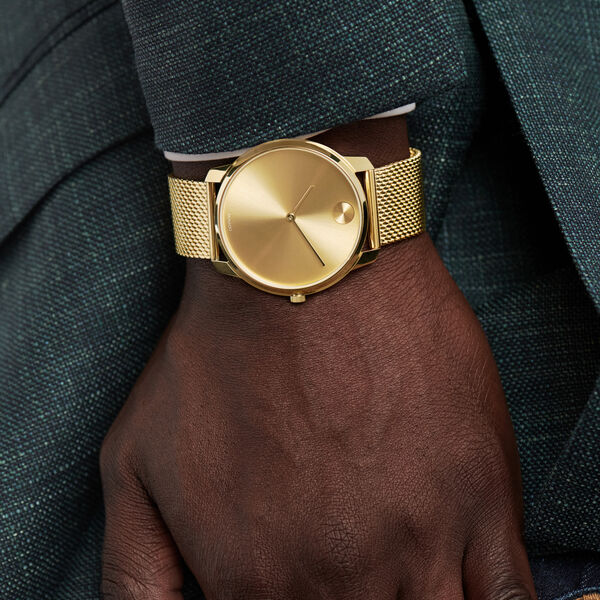 Movado Bold gold watch worn on wrist with jacket sleeve
