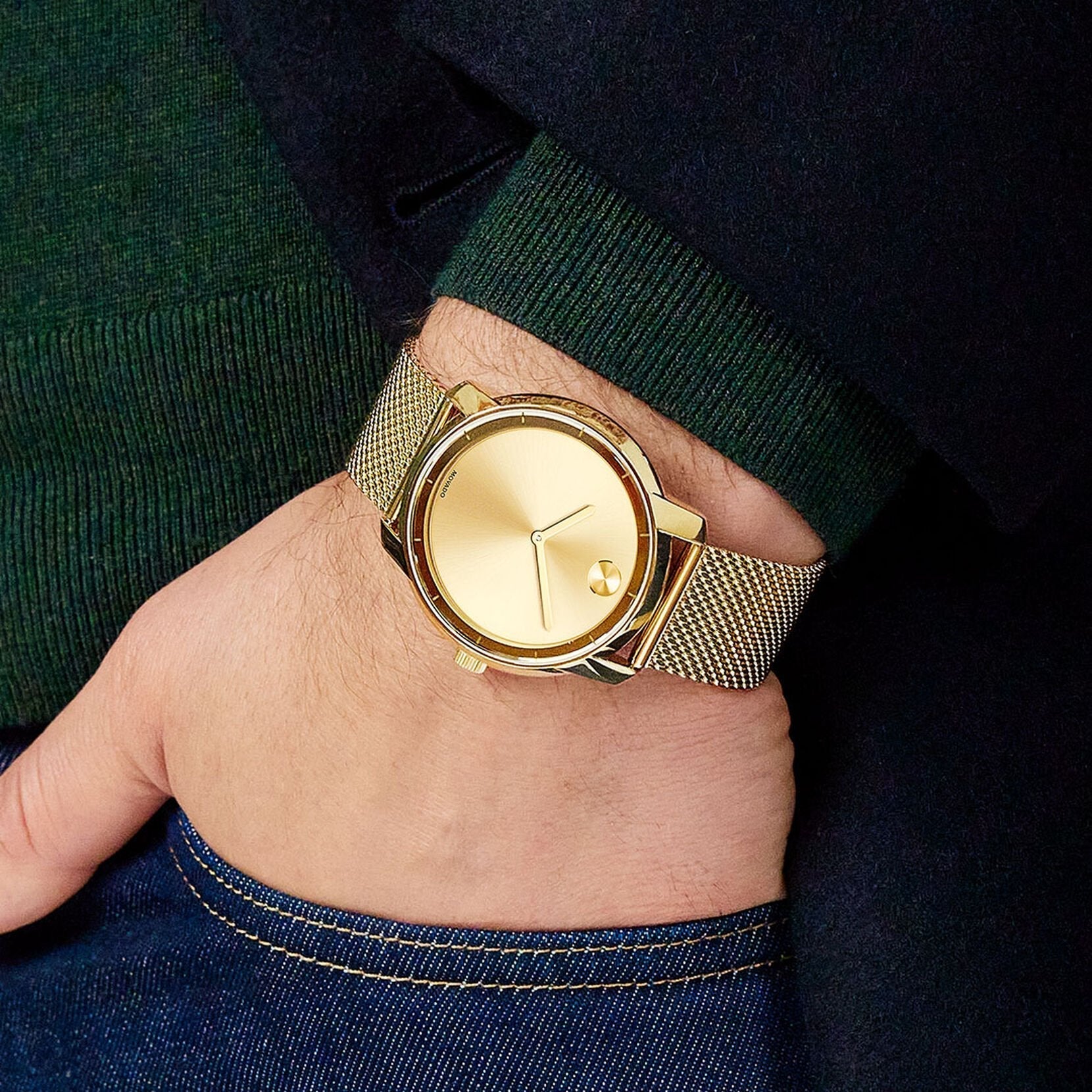Movado Bold gold men's watch on wrist with casual attire