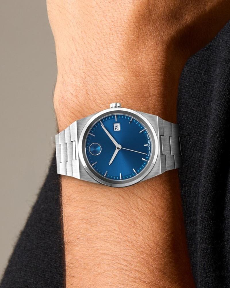 Movado BOLD Quest watch worn on wrist showing blue dial and silver bracelet