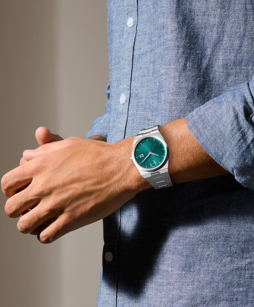 Movado BOLD Quest 40mm watch worn on wrist with teal dial and stainless steel bracelet