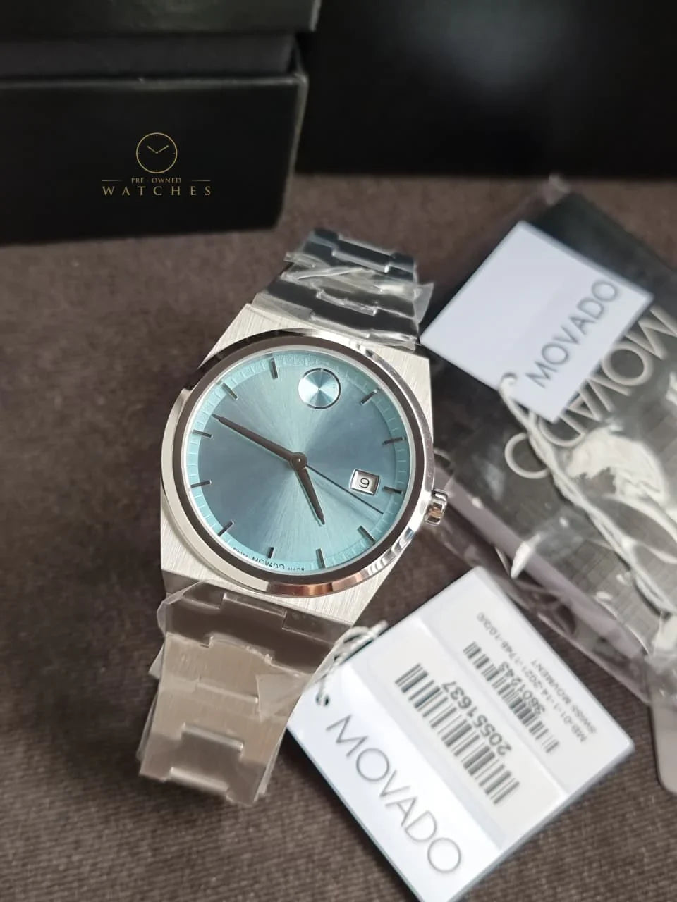 Movado BOLD Quest watch displayed with original packaging, warranty cards, and presentation box