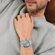 Movado BOLD Quest seafoam blue dial watch worn on wrist, shown on male model with stone-colored sleeve