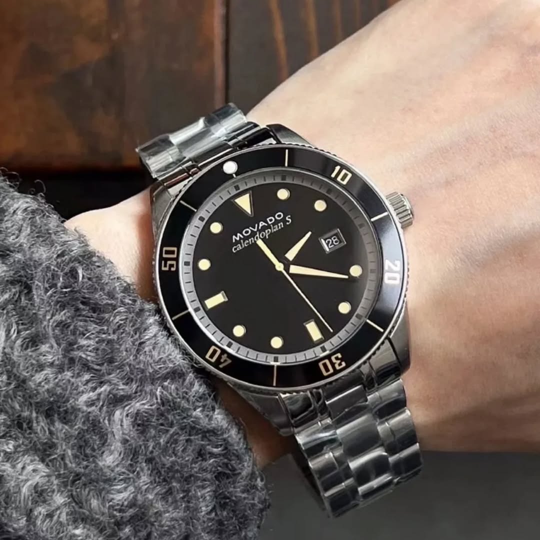 Movado Heritage black dial men's watch on wrist with steel bracelet and rotating bezel