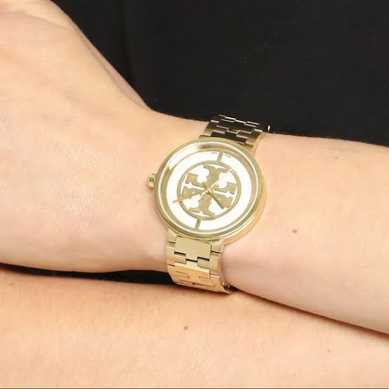 Reva gold-tone watch worn on wrist showing logo dial and bracelet fit