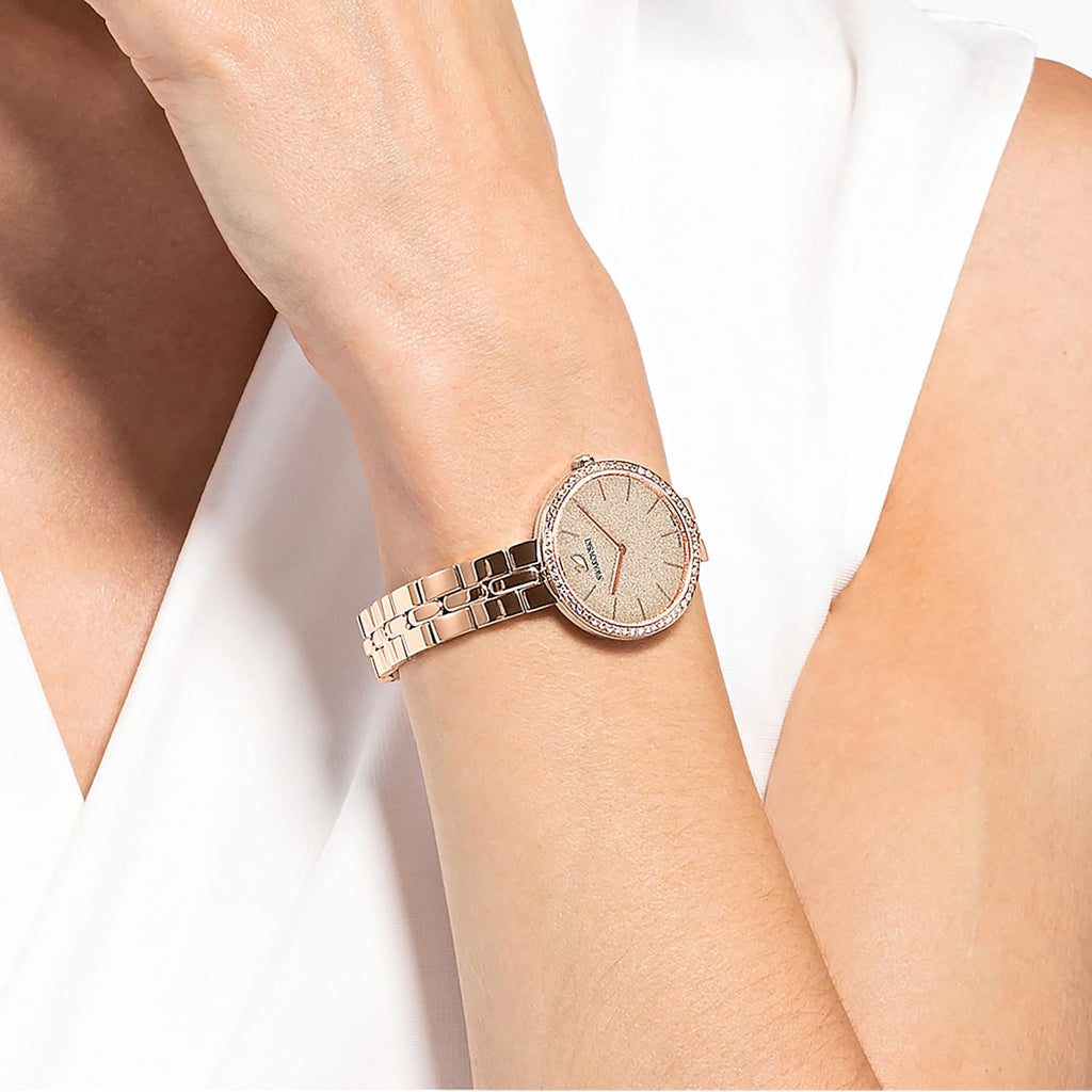 Swarovski Cosmopolitan rose gold watch styled on wrist with white sleeve