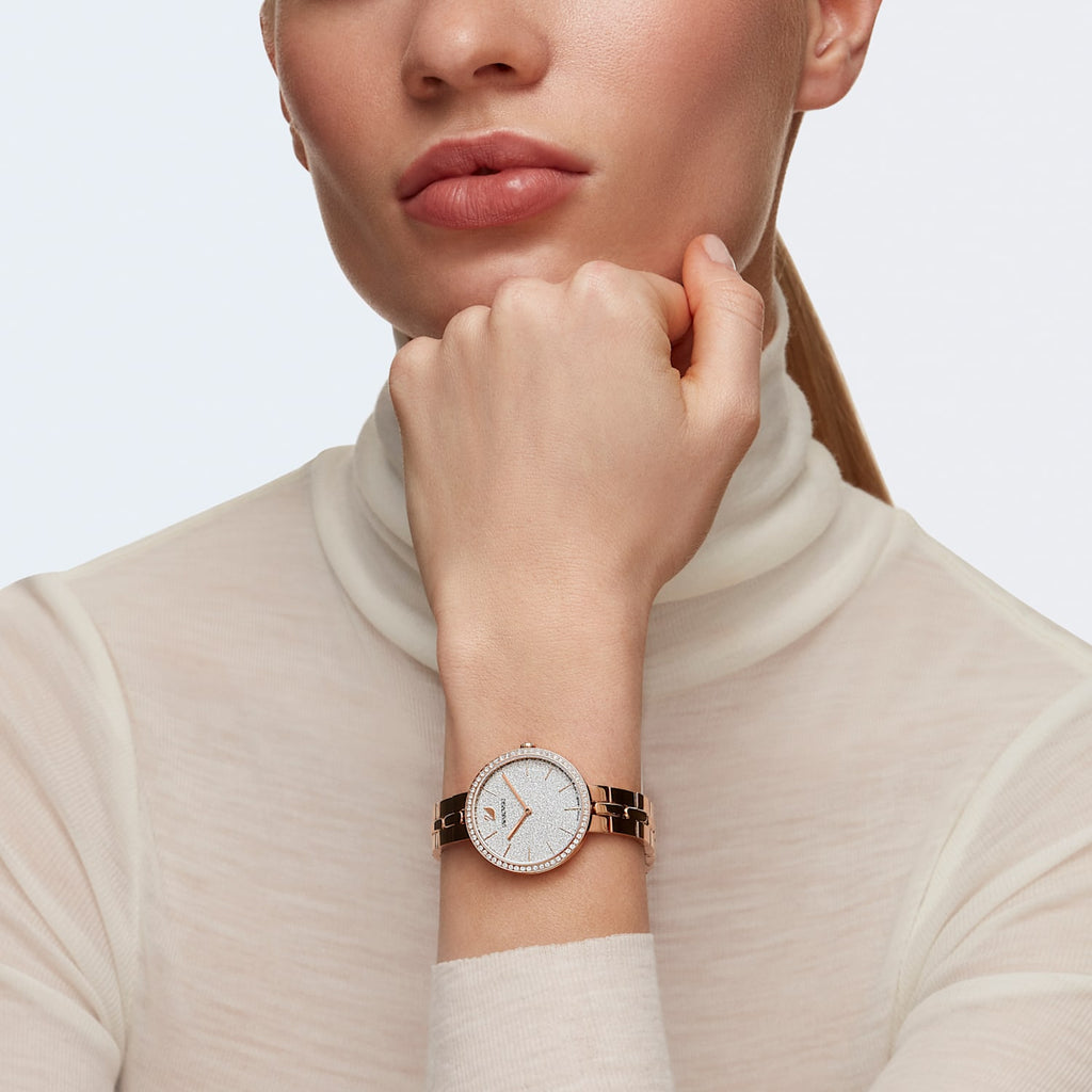 Swarovski Cosmopolitan rose gold watch worn on wrist with cream turtleneck