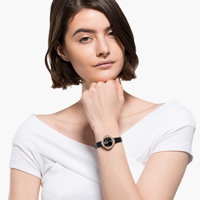 Woman wearing Swarovski Crystalline Aura rose gold watch with black dial