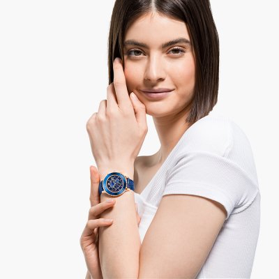Woman wearing Swarovski Crystalline Glam watch with blue dial and rose gold case on wrist