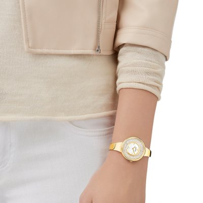 Swarovski Crystalline Pure gold women's watch worn on wrist with gold tone bangle strap