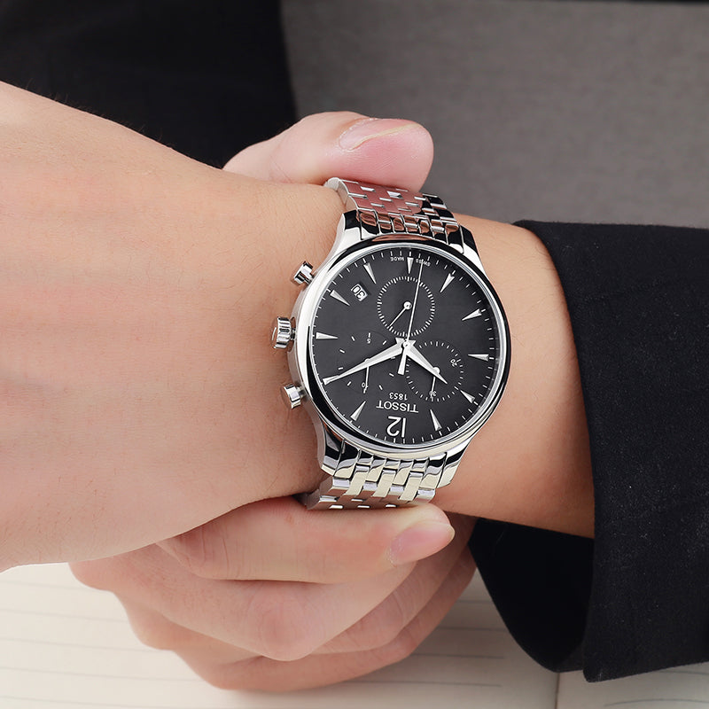 Tissot Tradition chronograph watch worn on wrist showing black dial and steel bracelet