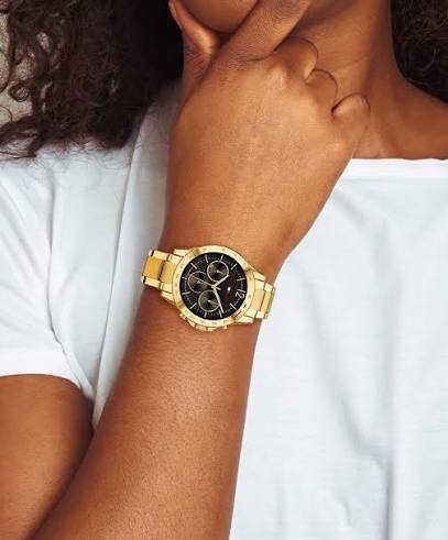 Gold-tone Tommy Hilfiger chronograph watch with black dial worn on wrist