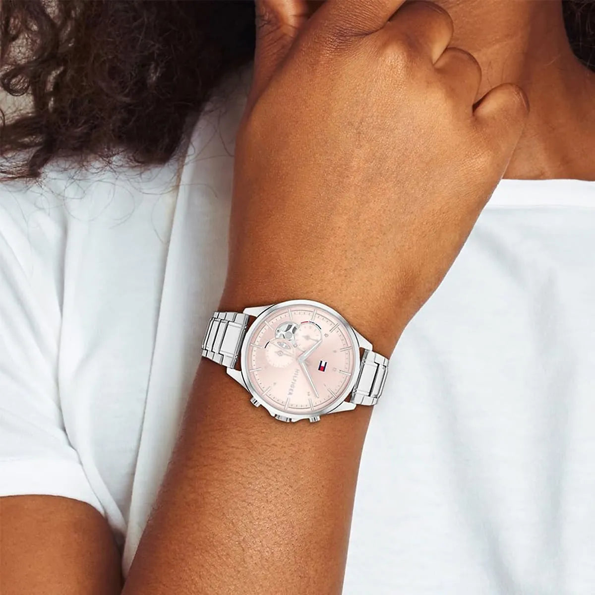 Tommy Hilfiger multifunction watch with pink dial worn on wrist with white sleeve