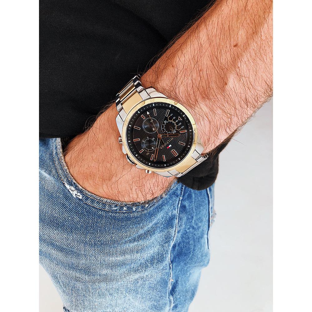 Tommy Hilfiger dual-tone men's chronograph watch worn on wrist with denim and black sleeve
