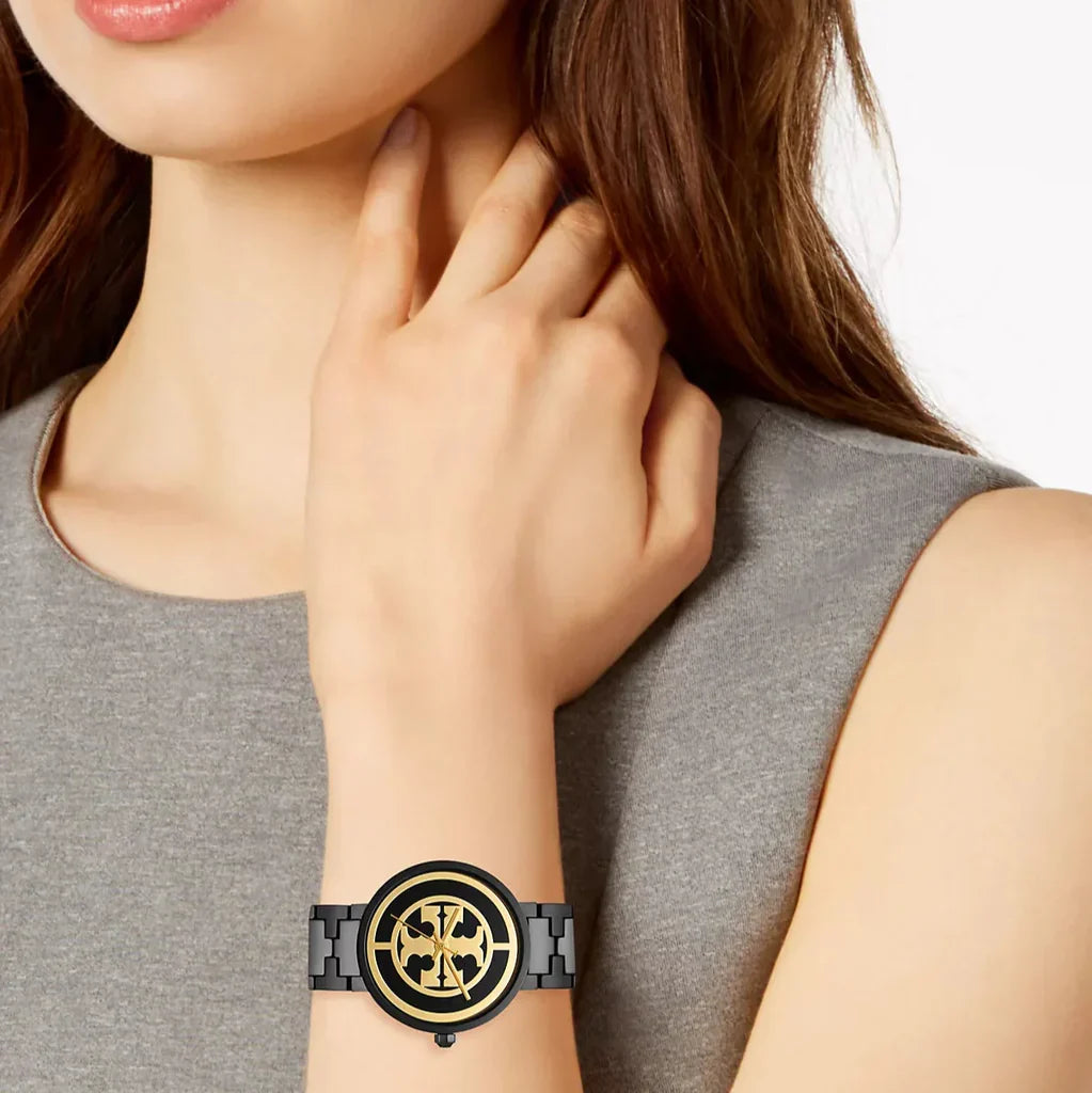Tory Burch Reva watch on wrist worn by woman with black dial and gold accents