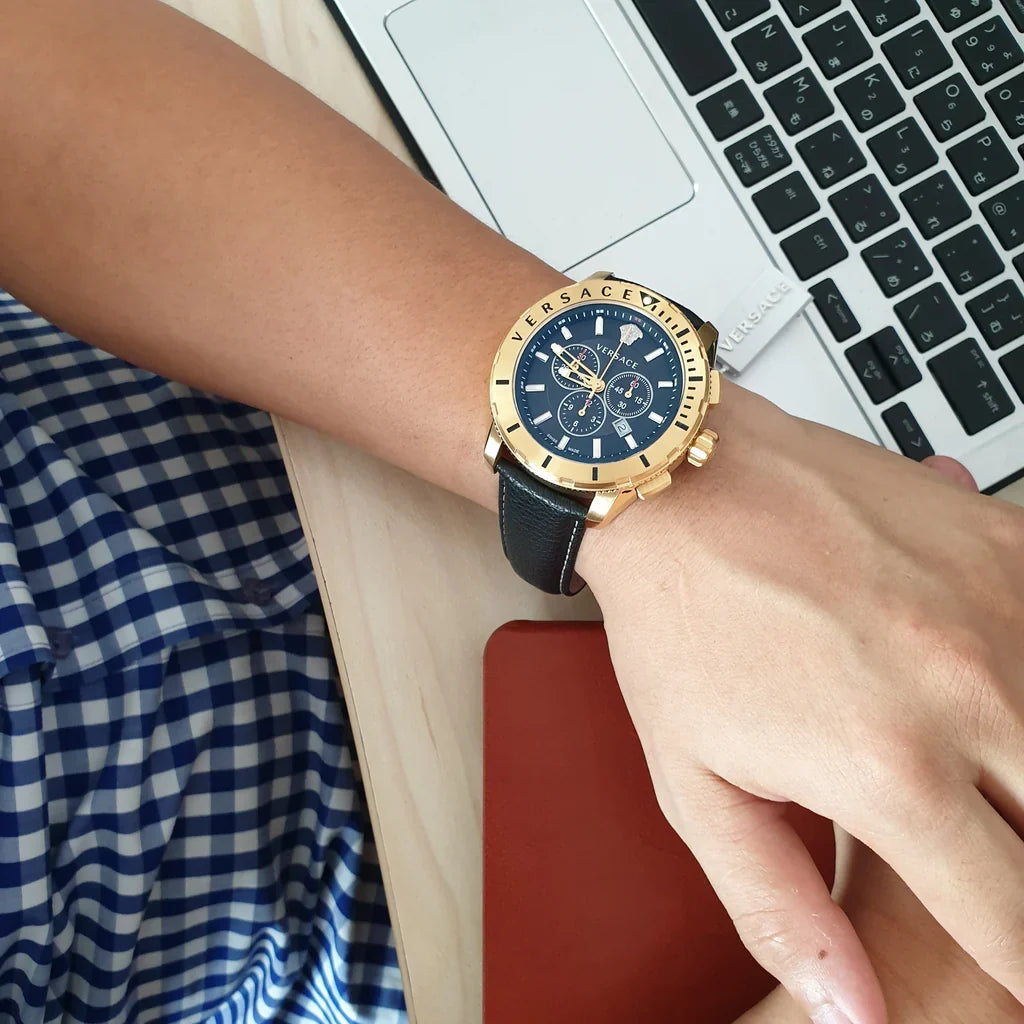 Versace chronograph watch worn on wrist with blue leather strap and gold case