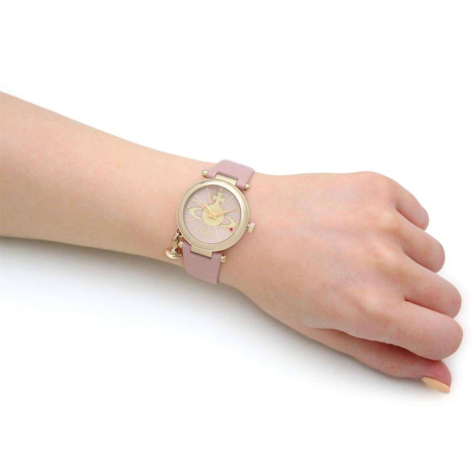 Vivienne Westwood Orb II watch worn on wrist, showing pink leather strap and gold case with orb dial design