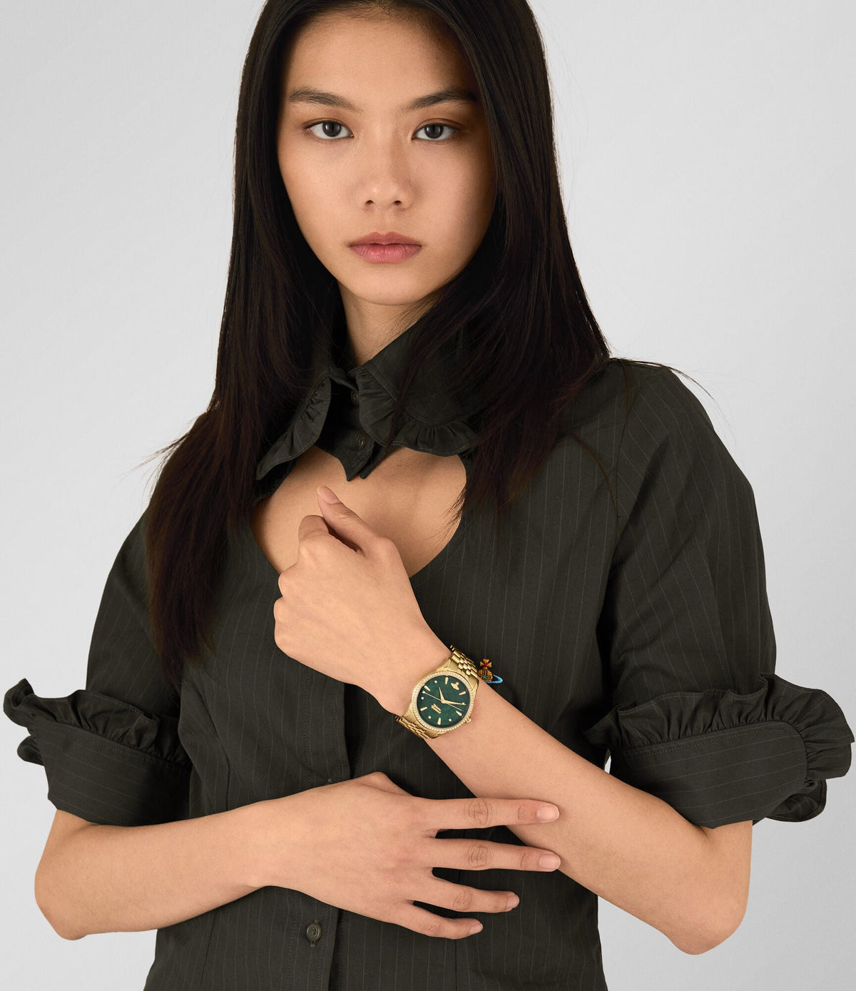 Woman wearing The Wallace watch with green dial and gold bracelet on wrist