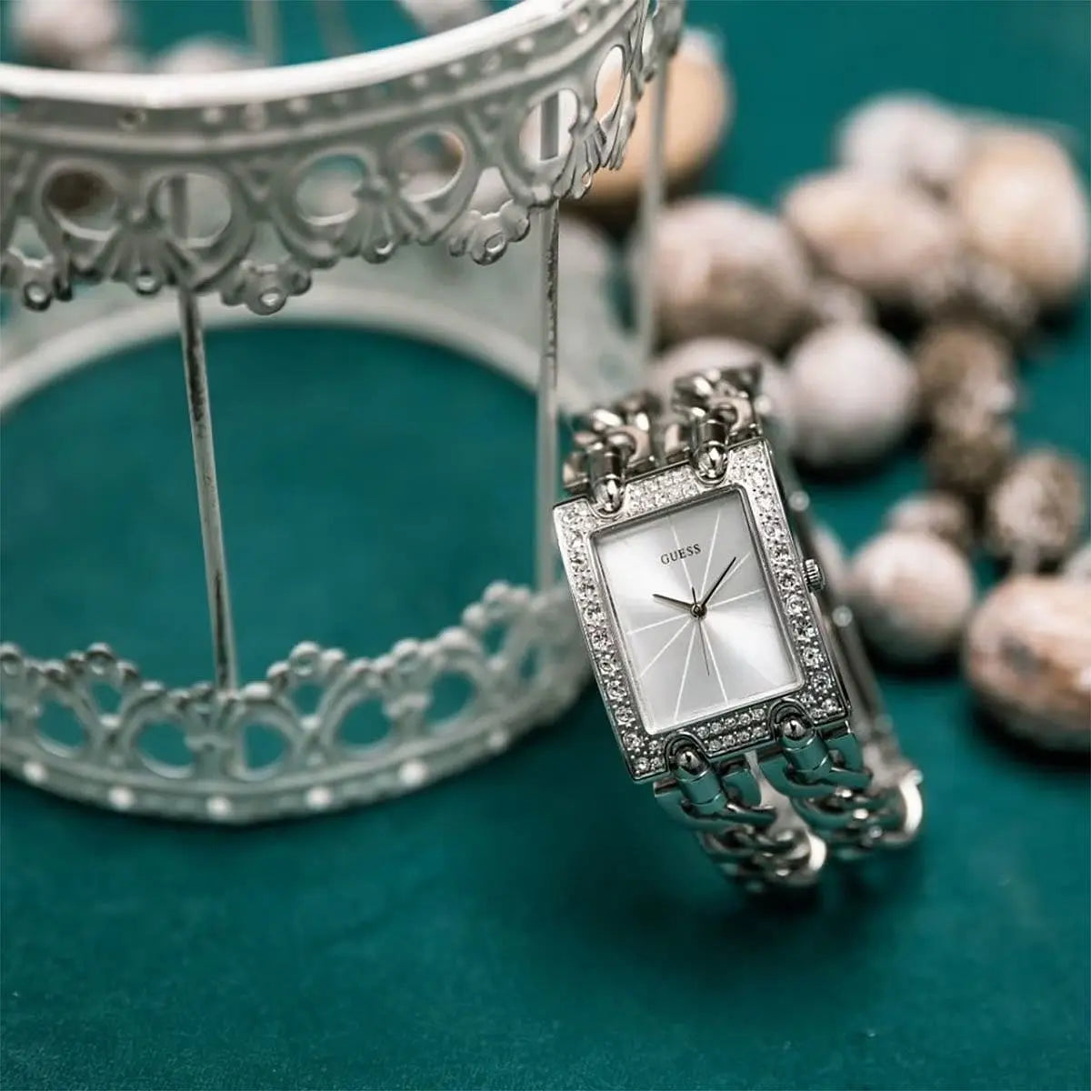 Close-up detail of Guess W1121L1 watch dial with crystals and chain strap accent