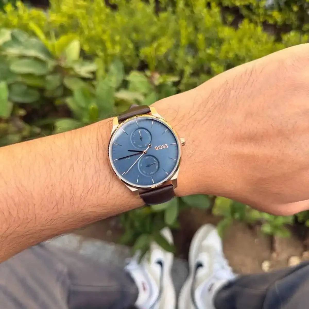 Hugo Boss Tyler quartz watch on wrist with blue dial and brown leather strap in outdoor setting