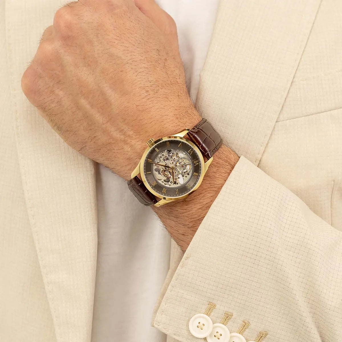 Hugo Boss skeleton automatic watch worn on wrist with cream-colored dress shirt and jacket