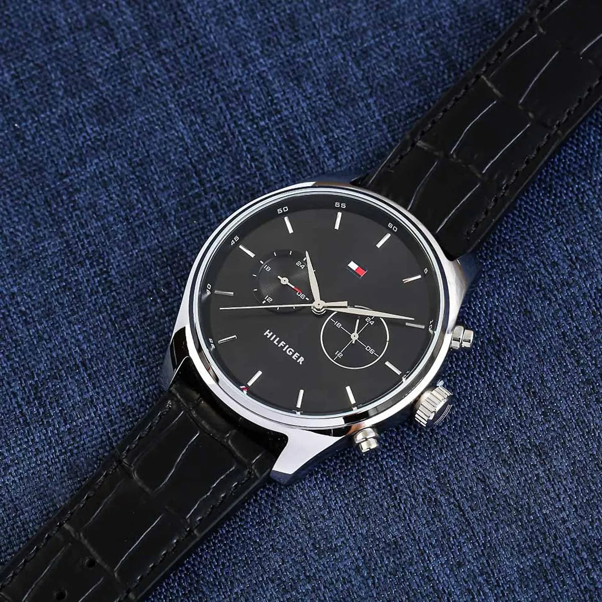Tommy Hilfiger black dial watch worn on wrist with navy fabric background