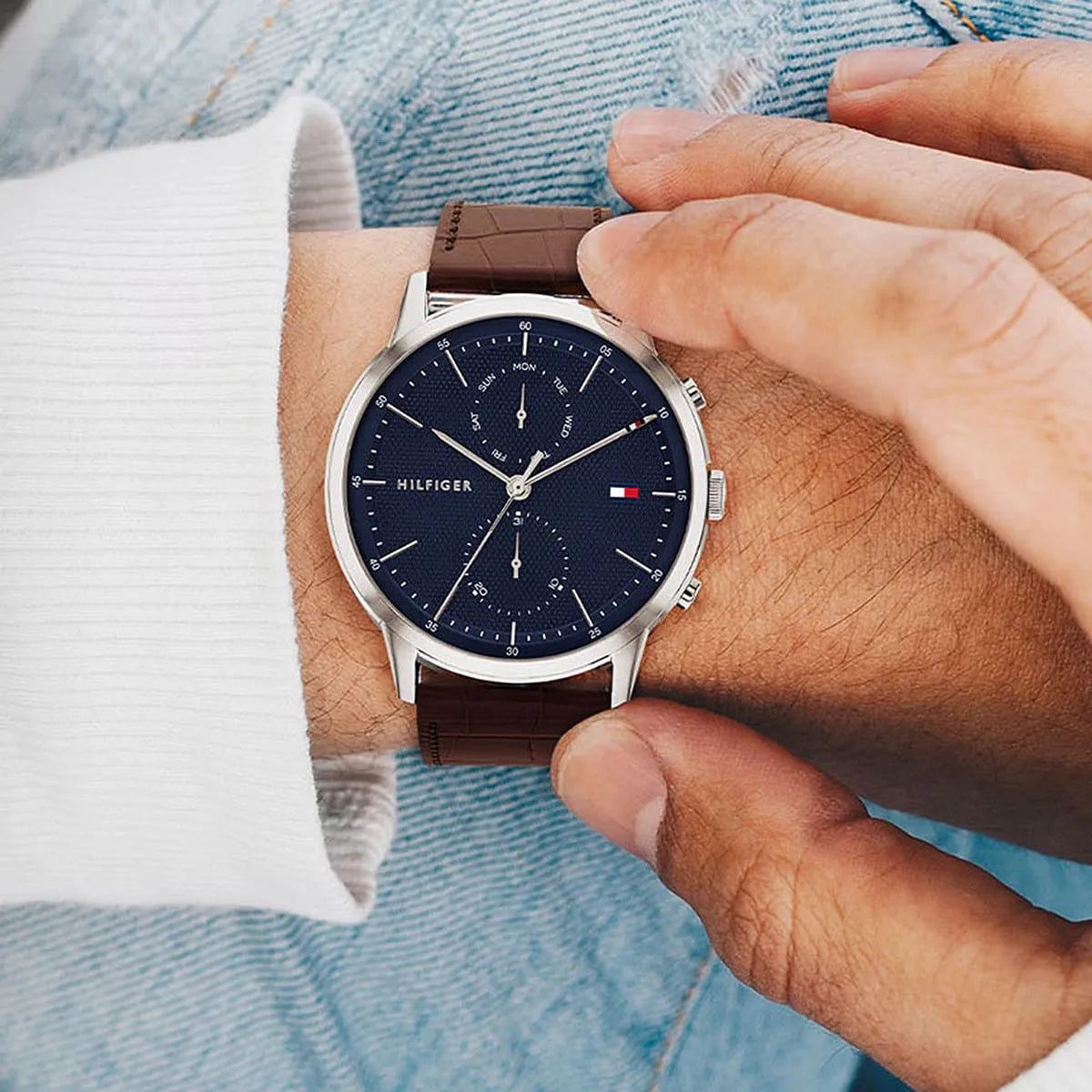 Watch worn on wrist showing dial and brown leather strap in casual setting