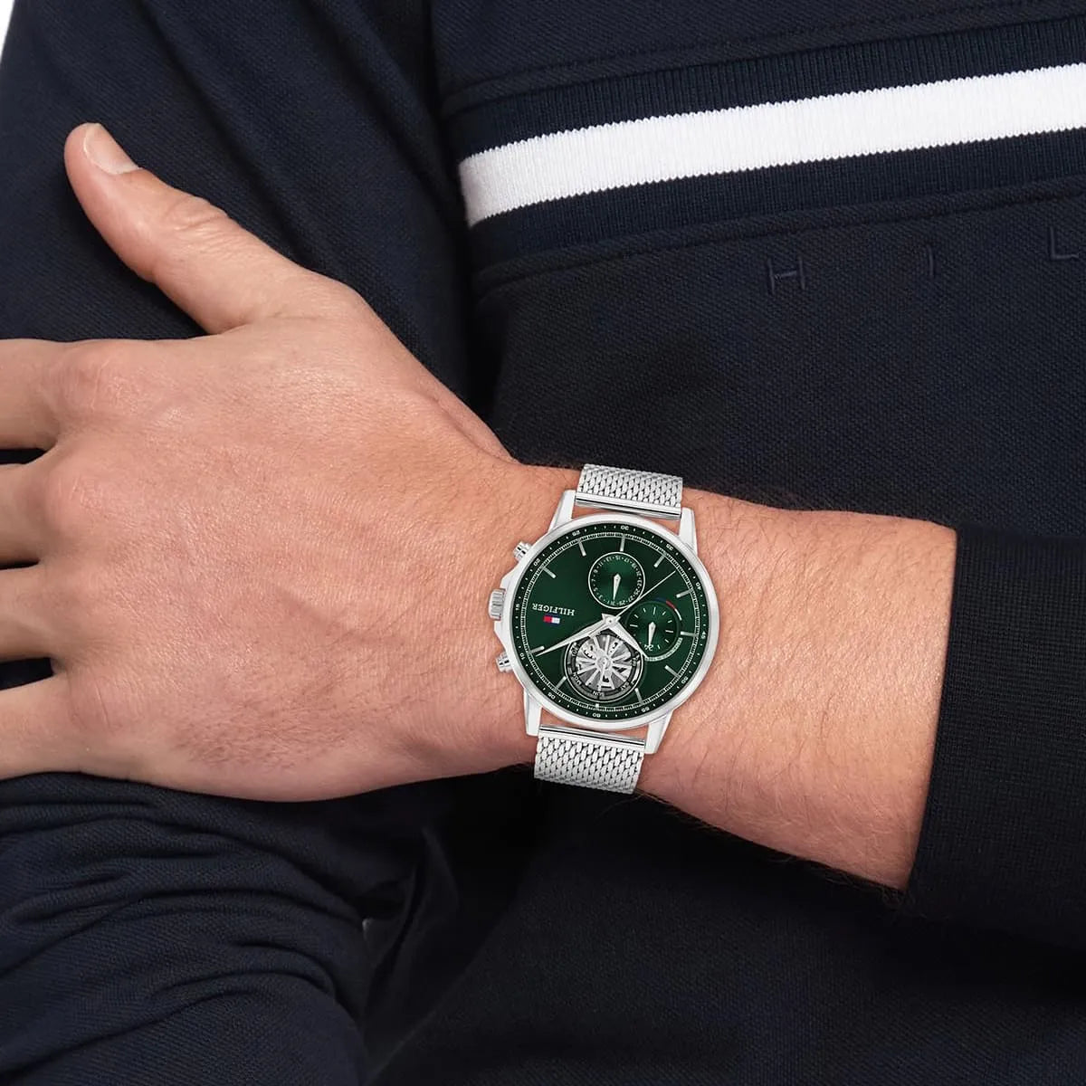 Wrist-worn view of Tommy Hilfiger watch with green dial and chronograph subdials on silver mesh strap
