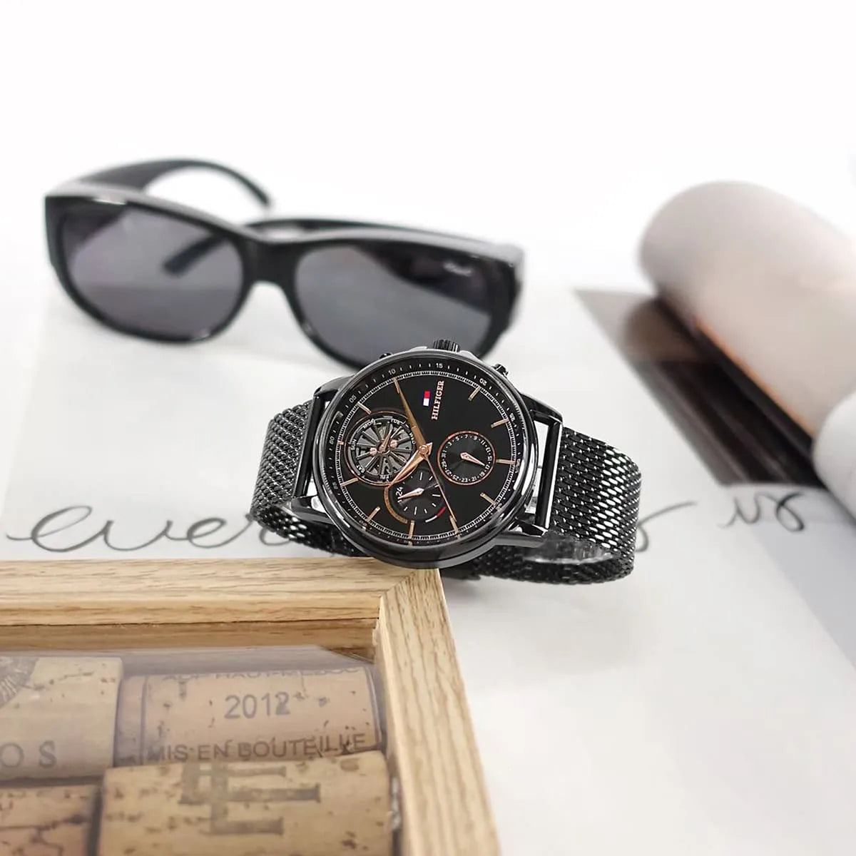 Tommy Hilfiger Stewart watch displayed with sunglasses and wooden box