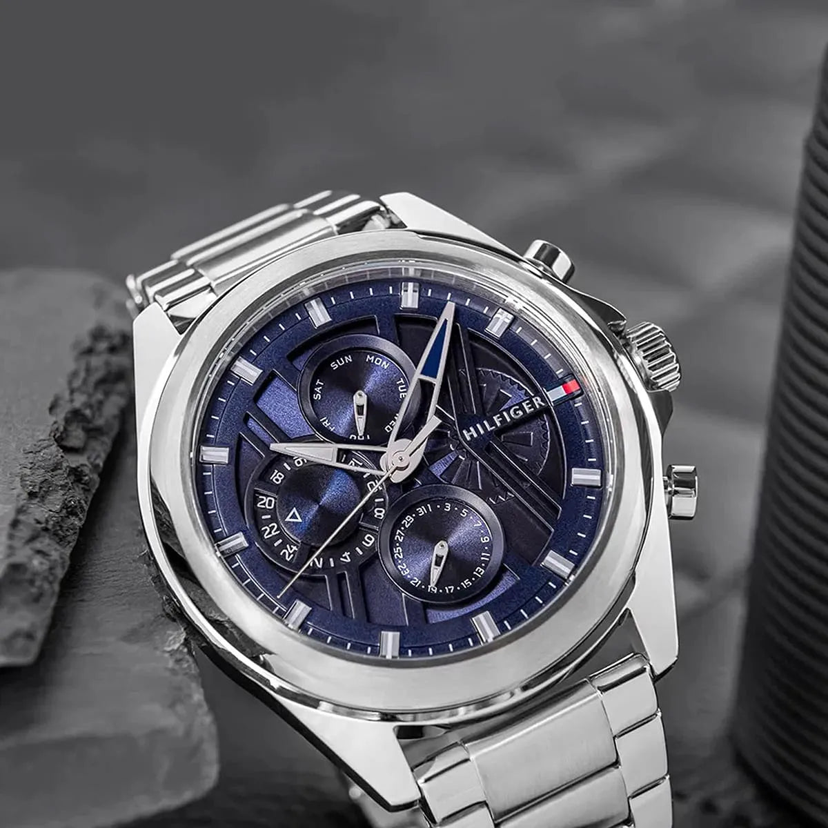 Tommy Hilfiger chronograph watch with navy dial on textured surface, artistic styling