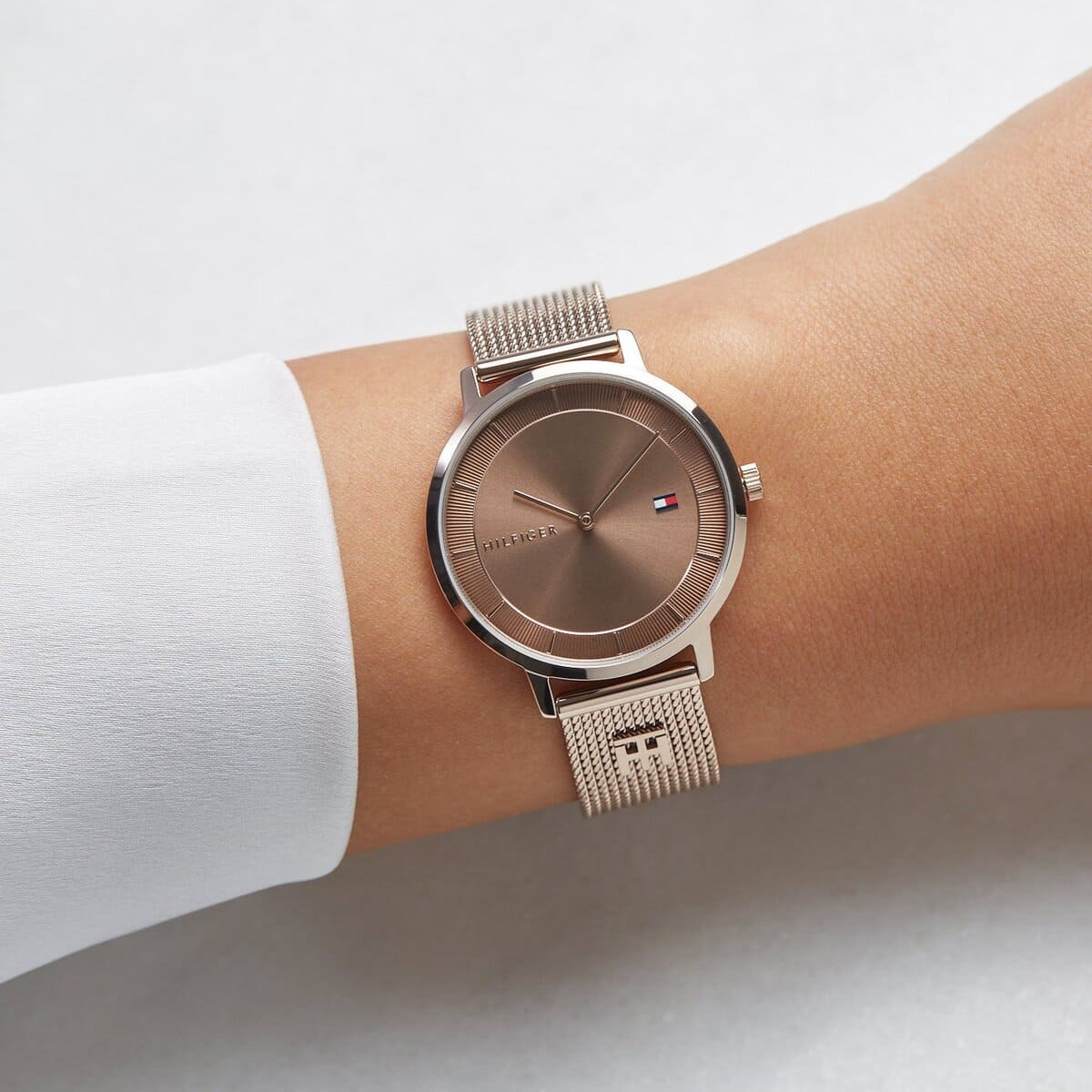 Tommy Hilfiger carnation gold women's watch worn on wrist with light taupe dial and mesh strap