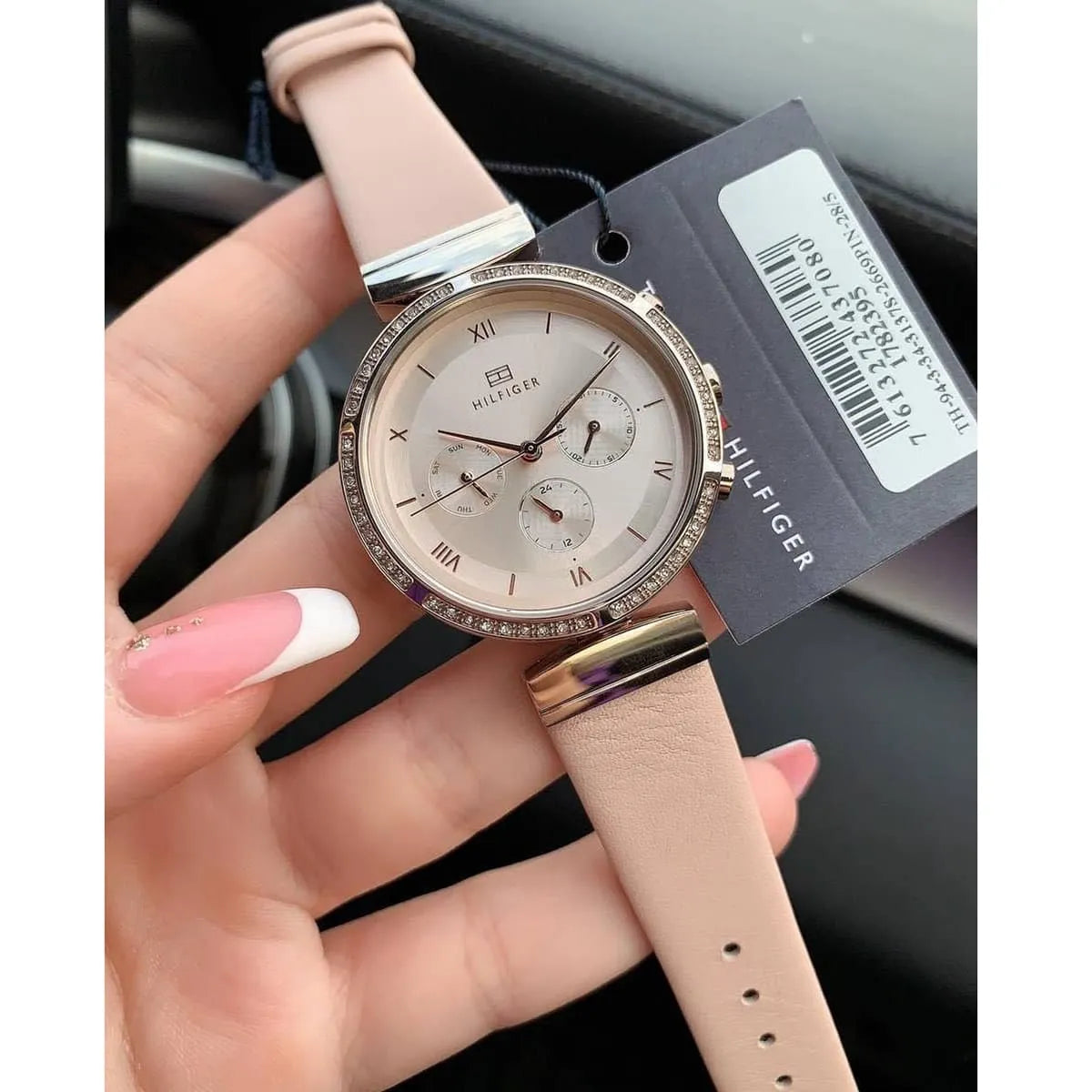 Tommy Hilfiger Luna watch on wrist with product tag, showing blush dial and pink leather band