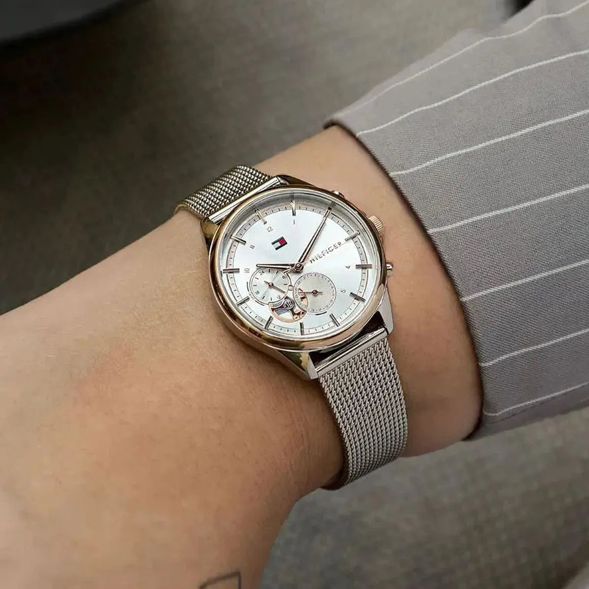 Tommy Hilfiger women's watch worn on wrist, showing silver dial and mesh strap in natural light
