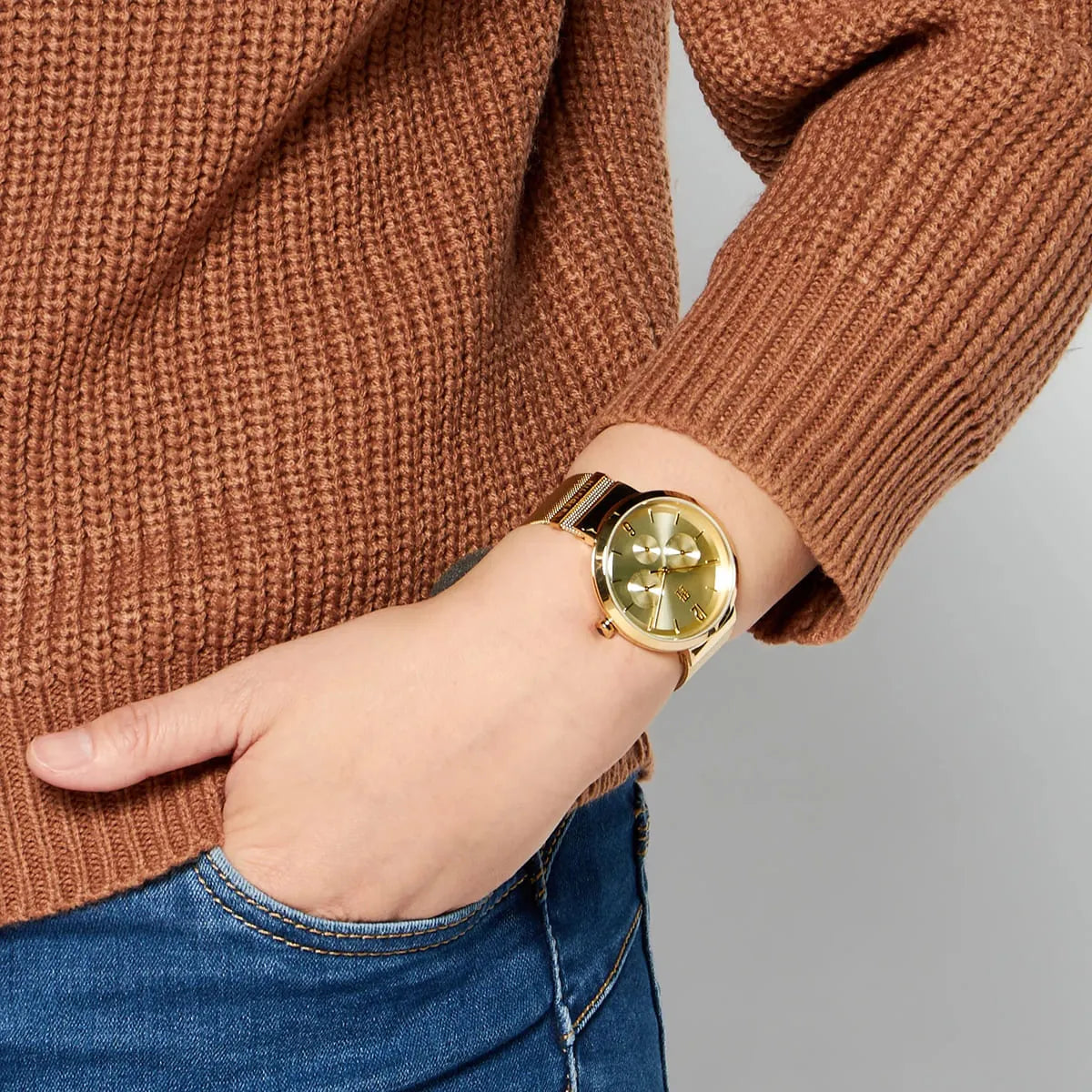 Tommy Hilfiger Lidia gold dial watch worn on wrist with rust-colored sweater
