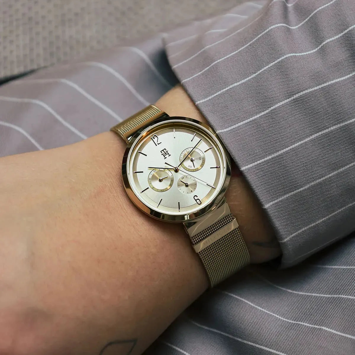 Tommy Hilfiger Lidia gold watch worn on wrist with striped shirt