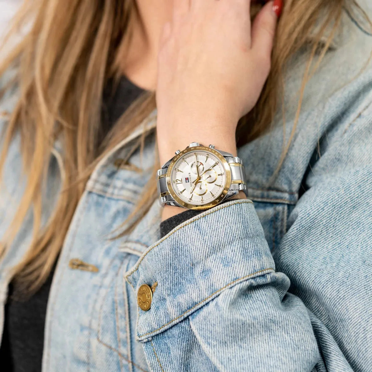 Two-tone Tommy Hilfiger chronograph watch worn on wrist with denim jacket